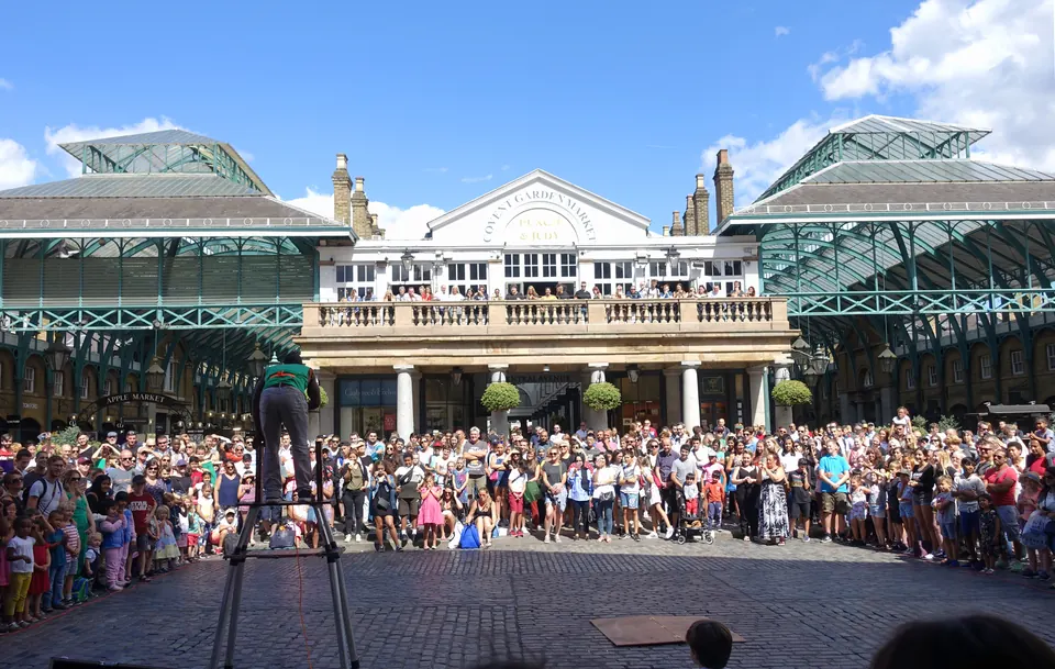 People gathered in Covent Garden Piazza in London watching a street performance.