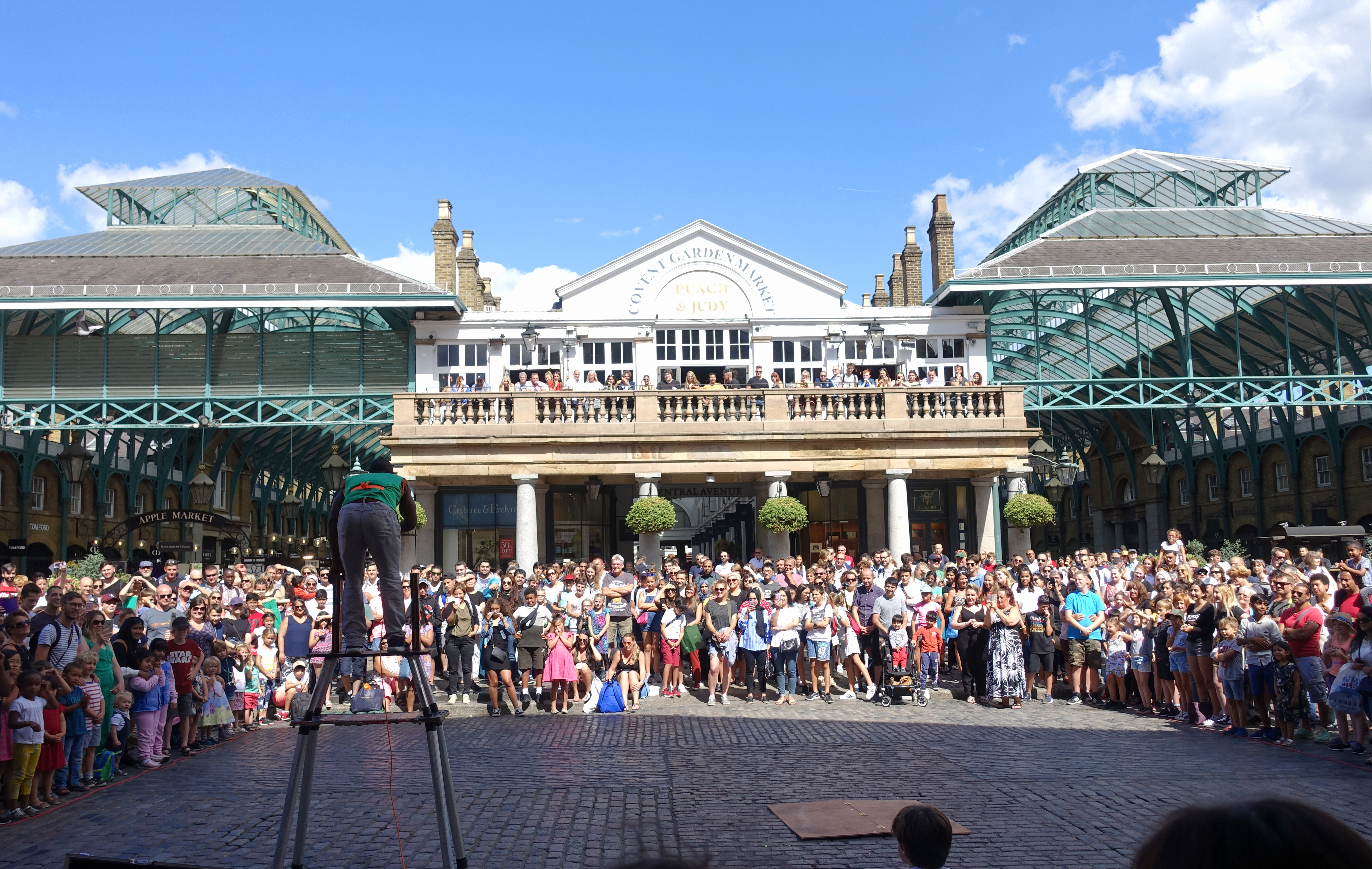 People gathered in Covent Garden Piazza in London watching a street performance.