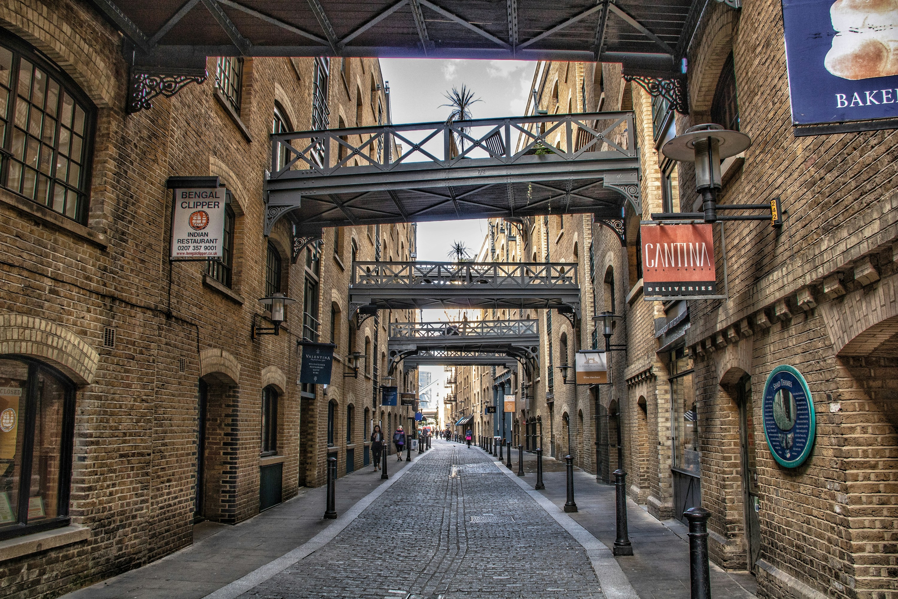 Historic warehouse buildings and overhead bridges along Shad Thames near London Bridge.