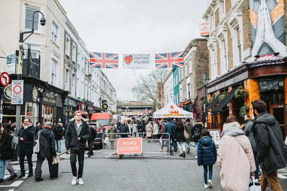 People walking along Portobello Road in Notting Hill among colourful shops and market streets.