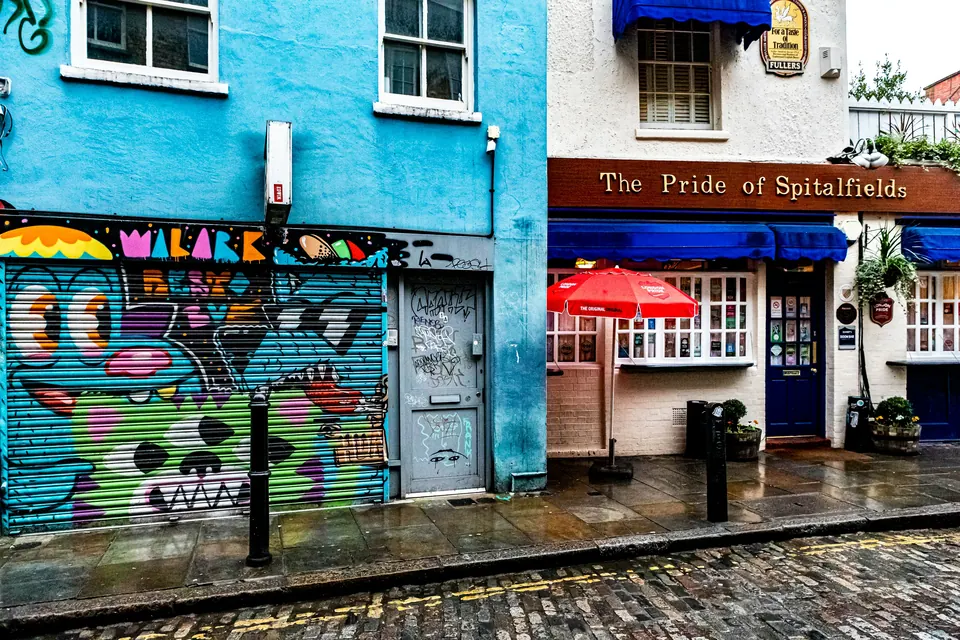 Pedestrians, independent shops and colourful street art along Brick Lane in Shoreditch.